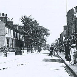 A lady walking down Mill Road in Cambridge wearing a large hat